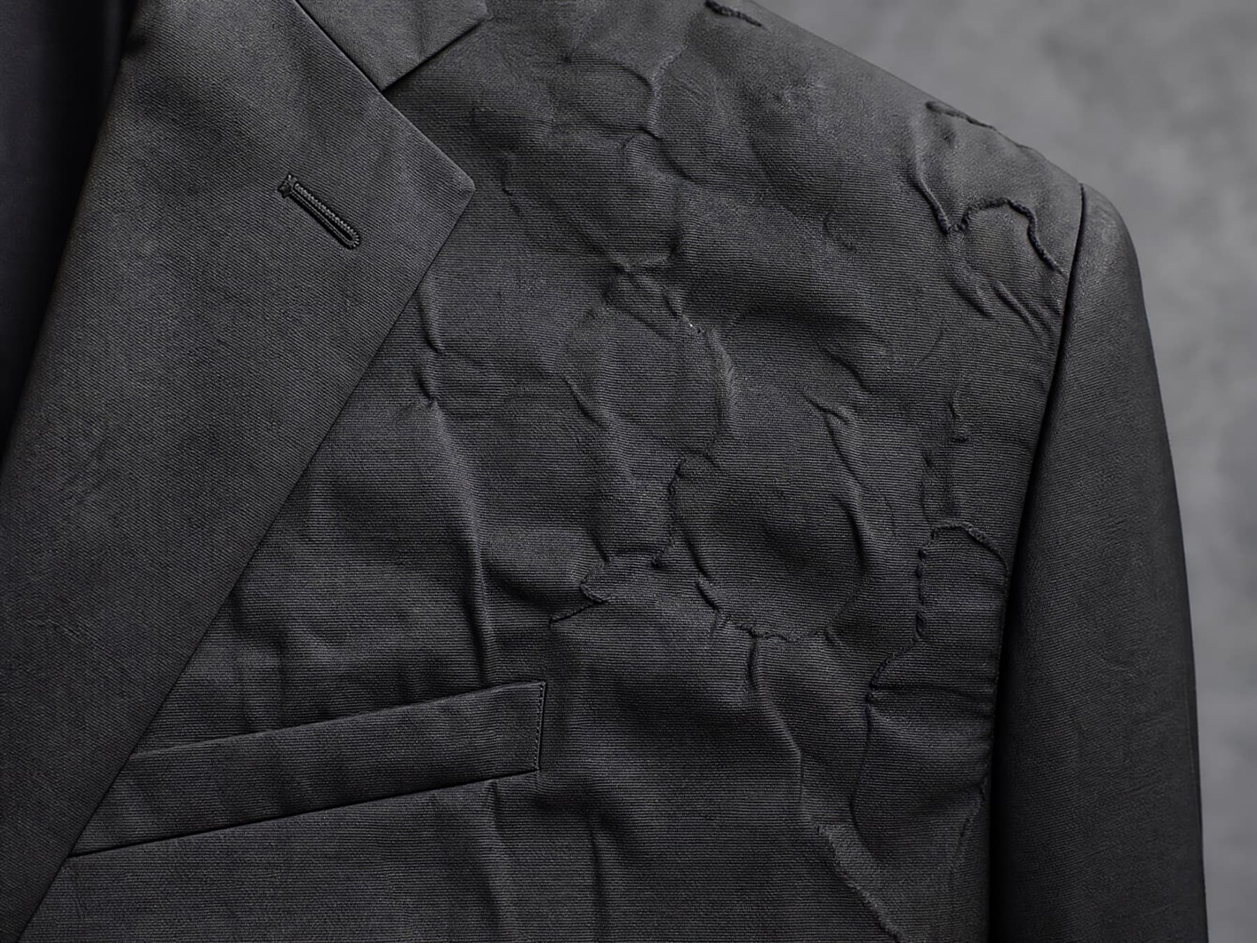 Raking light across a fused chest panel that has delaminated into visible ripples after repeated dry cleaning